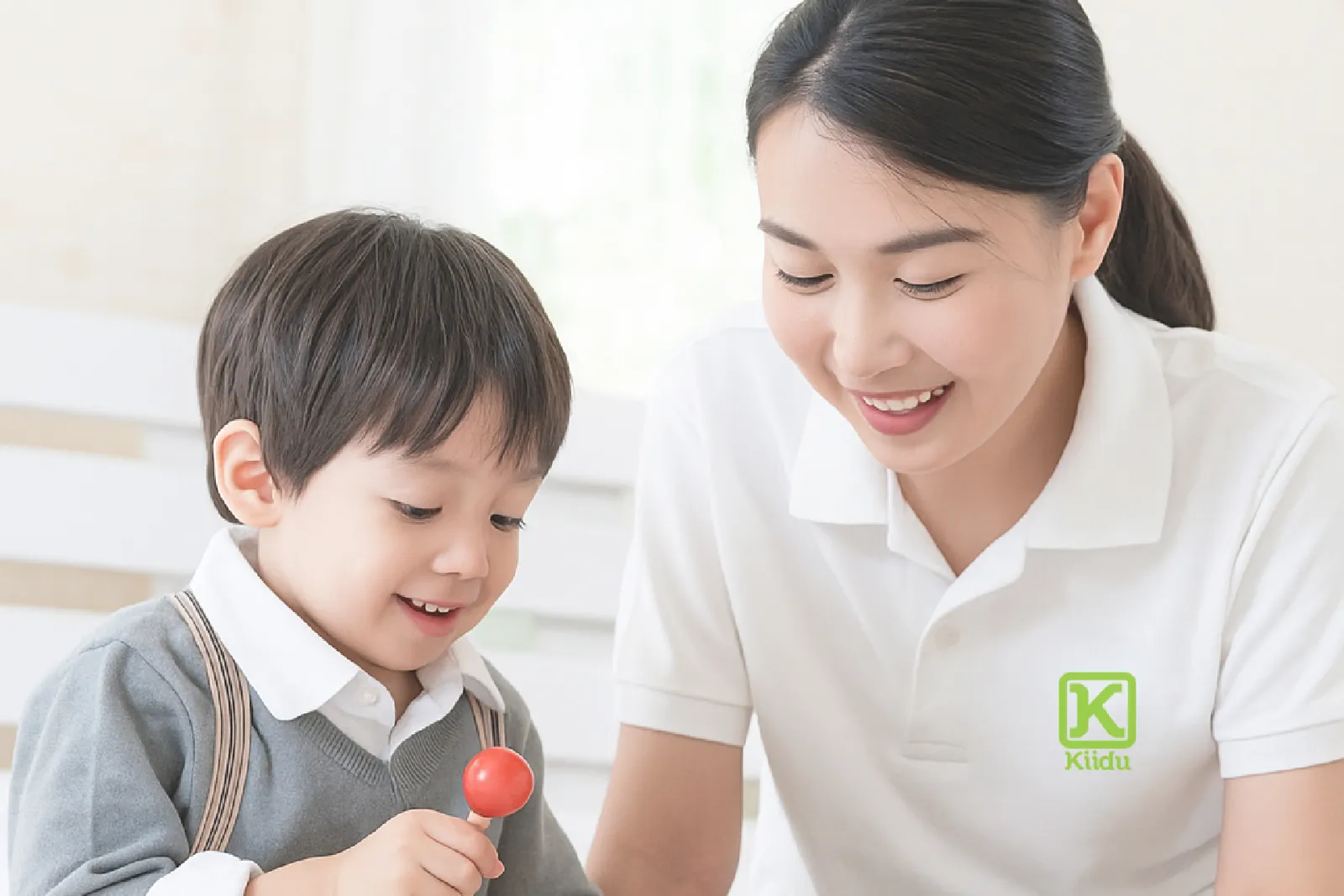 พี่เลี้ยงเด็ก Kiidu ในชุดยูนิฟอร์ม Kiidu เล่นตัวต่อกับเด็กที่บ้านในประเทศไทย
